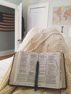 an open book sitting on top of a bed next to a white door in a bedroom