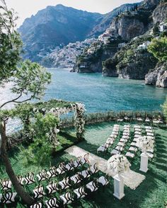 an outdoor ceremony set up with chairs and flowers on the lawn next to the water