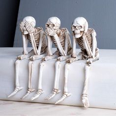 four skeleton figurines sitting on a white surface