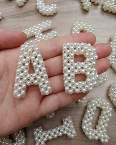 someone is holding letters made out of pearls