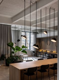 an office with wooden tables and hanging lights in the ceiling, along with black chairs