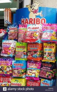 many bags of candy are stacked on top of each other in front of a sign