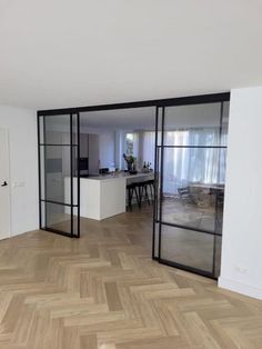 an open living room and kitchen area with wood flooring, sliding glass doors to the dining room