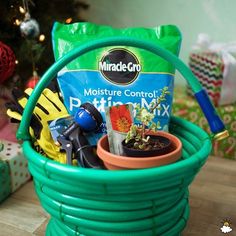 a green basket filled with gardening supplies next to a christmas tree