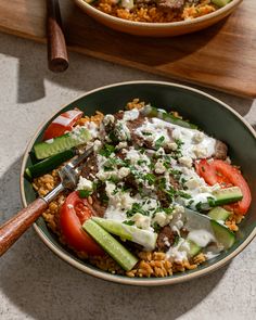 a bowl filled with rice, cucumbers and tomatoes