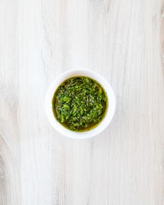 a white bowl filled with pesto on top of a wooden table