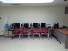 there are many computers on the desks in this office room, and one is empty