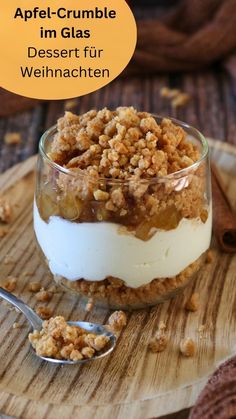 an apple crumble dessert in a small glass dish on a wooden plate with a spoon