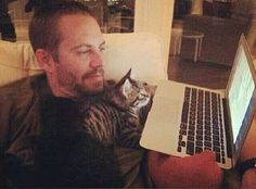 a man sitting in front of a laptop computer with a cat laying on his lap