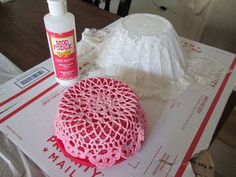 there is a crochet doily on the table next to some toilet paper