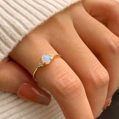 a woman's hand wearing a gold ring with an opal stone on it