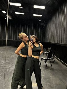 two women standing in front of a mirror taking a selfie