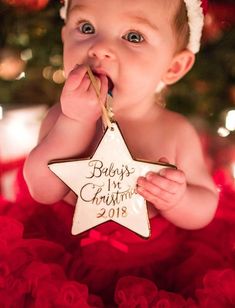 a baby wearing a santa hat and holding a star ornament