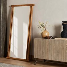 a mirror sitting on top of a wooden cabinet next to a vase