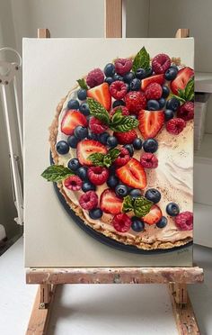 a painting of a pie with berries and mint leaves on it sitting on an easel