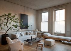 a living room filled with furniture and a tree in the middle of the room on top of a hard wood floor