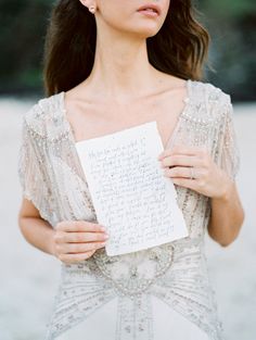 a woman holding a piece of paper with writing on it in front of her face