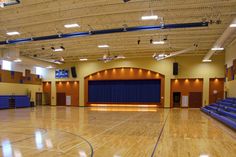 an empty basketball court with blue seats