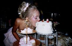 a woman is blowing out candles on a cake that has been decorated with pink and white icing