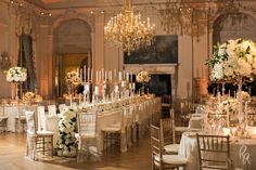 an elegant wedding setup with white flowers, candles and chandeliers in the ballroom