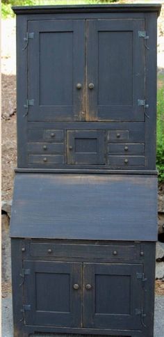 an old wooden cabinet with two doors and drawers on the bottom, next to another piece of furniture