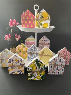 there are many small houses on the table with flowers and lemons in front of them