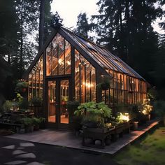 a small greenhouse in the middle of a forest with lights shining on it's windows