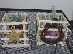 two wooden crates with plants in them sitting on a black tableclothed surface, one has a gold star and the other has a wreath