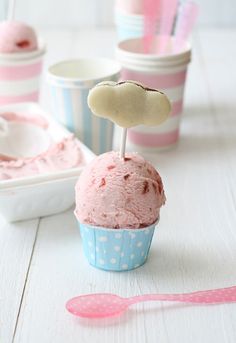 there is a cupcake with pink icing in it and two spoons next to it