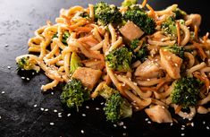 noodles and broccoli with sesame seeds on a black surface