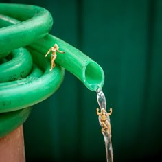 a green hose connected to a wooden post with a small figure on top of it