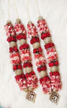 three necklaces with flowers and bells hanging from them on a white furnishing