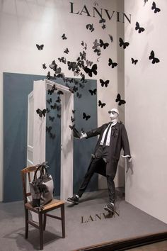 a mannequin dressed in a suit and tie standing next to a door with butterflies on it