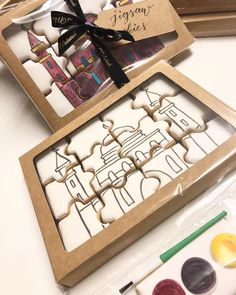 some cookies are in a box on a table with markers and paintbrushes next to it