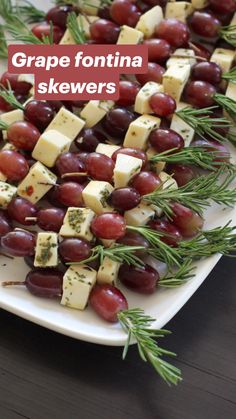 grapes, cheese and rosemary are arranged on a platter for an appetizer