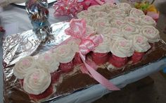 there is a large cake with white frosting and pink bows on it, sitting on a table