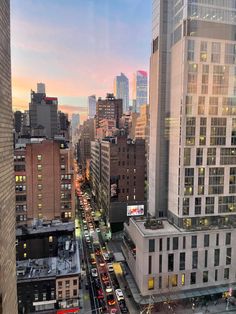 a city street filled with lots of traffic next to tall buildings in the evening time