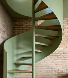 there is a spiral staircase in the corner of this room with brick walls and green paint