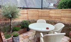 an outdoor patio with chairs, table and potted plants