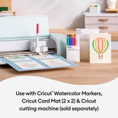 a cricut machine sitting on top of a wooden table next to some cards