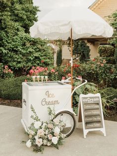 an ice cream cart is decorated with flowers and greenery, along with a sign that says ice cream