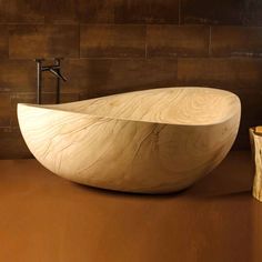 a large wooden bowl sitting on top of a counter next to a faucet