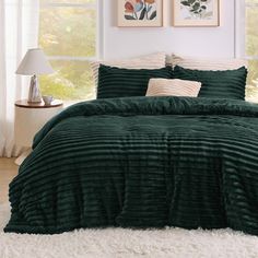 a bed with green comforter and pillows in a room