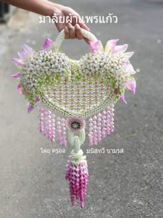 a person holding a pink and white purse with flowers hanging from it's handle