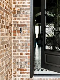 an open door to a brick building with a black handle on the front and side