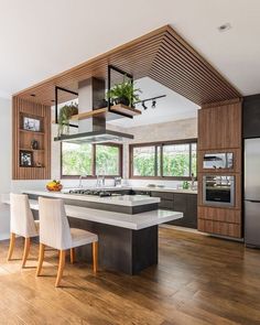 a modern kitchen with an island in the center and wooden cabinets on both sides, along with white chairs