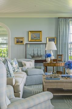 a living room filled with furniture and blue flowers on top of a wooden coffee table