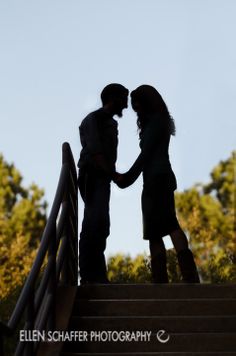 two people standing at the top of some stairs with their arms around each other as they shake hands