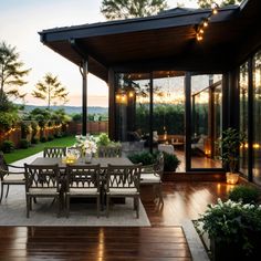 an outdoor dining area is lit up with string lights and surrounded by wooden decking