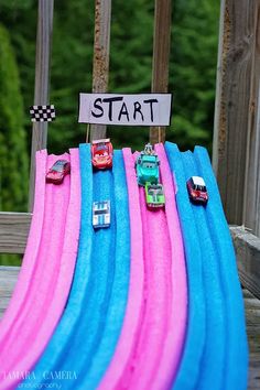 cars are lined up on top of blue and pink surfboards with a sign that says start